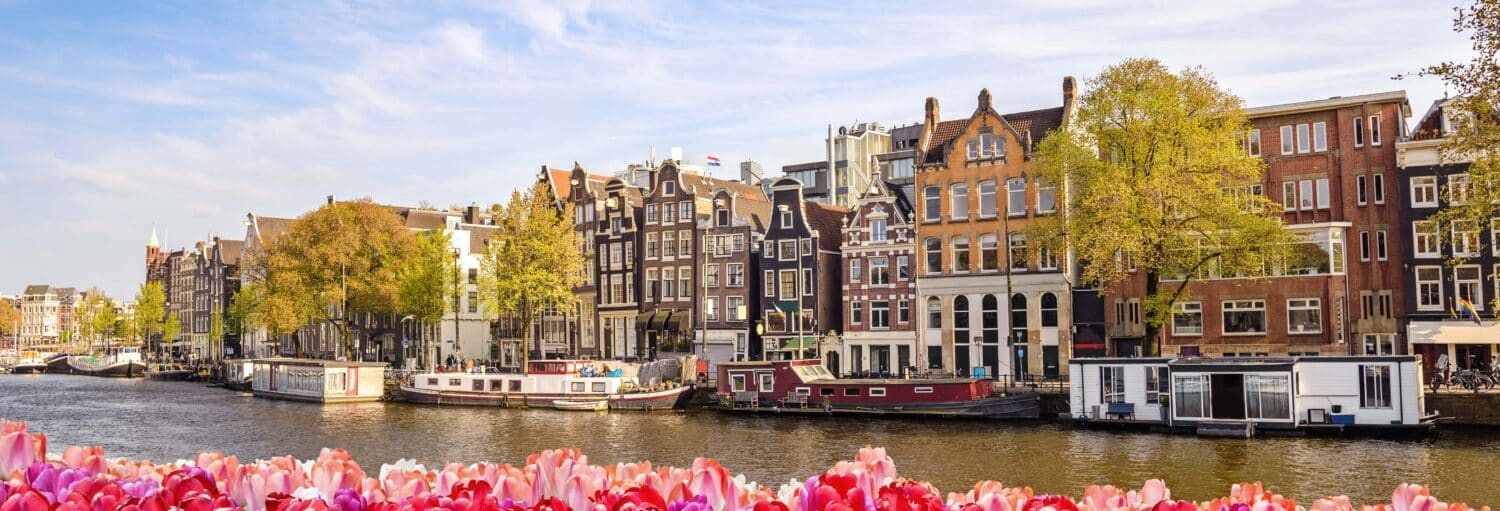 Vista de um canal em Amsterdam e casas na beirada. Escala em Amsterdam? Tour saindo do aeroporto