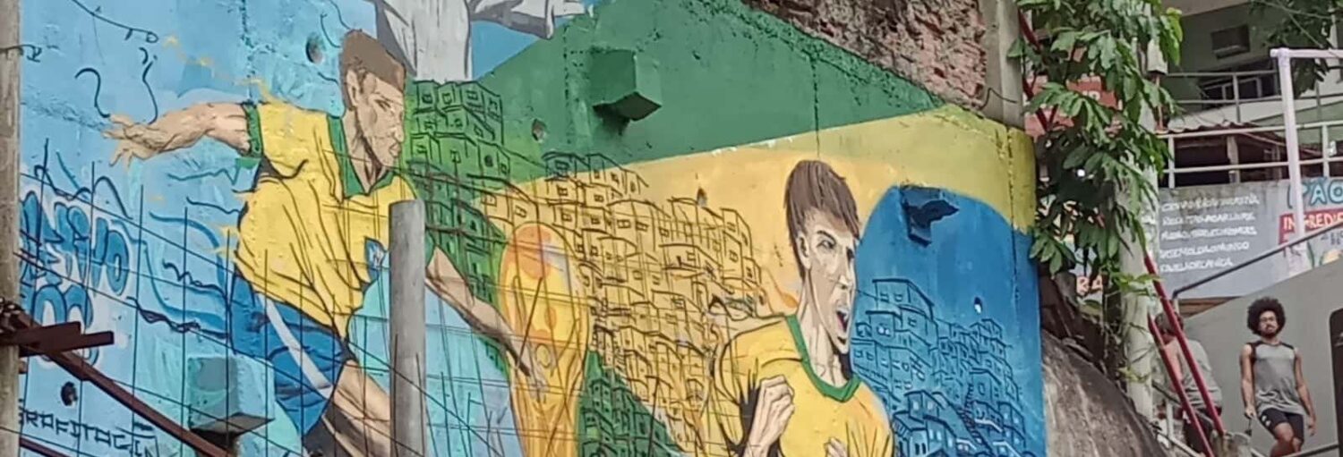 Um mural de jogadores de futebol com camisas amarelas decora uma parede no Tour pela favela da Babilônia, com a bandeira do Brasil atrás.