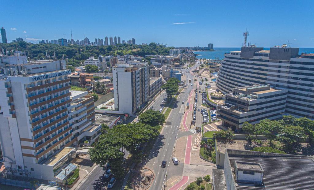 Vista aérea de uma rua da cidade com prédios altos, árvores e um vislumbre do oceano ao fundo.