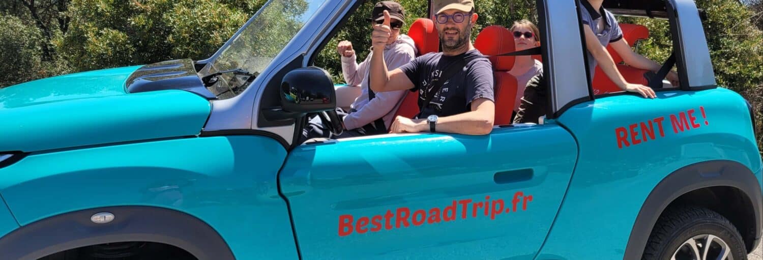 Quatro pessoas sentadas em um carro conversível azul com "BestRoadTrip.fr" e "RENT ME!" escritos na lateral. Um deles dá um sinal de positivo com o polegar. - Excursão privada a Mônaco de carro elétrico