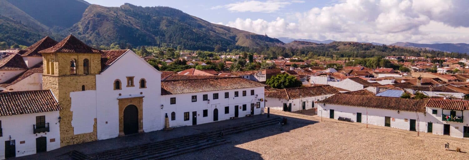 Uma igreja em estilo colonial e edifícios brancos alinham-se em uma praça de paralelepípedos em uma excursão de Bogotá a Villa de Leyva.