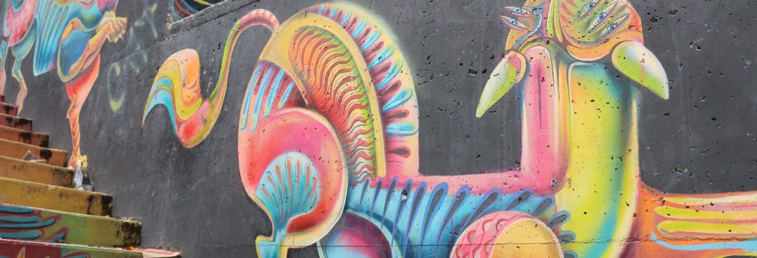 Mural colorido e abstrato de um animal estilizado com tons de neon brilhantes pintado em uma parede de concreto ao lado de escadas pintadas. a imagem ilustra o post sobre Free tour de street art por Bogotá.