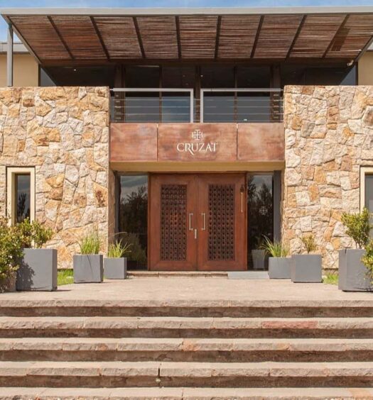 Edifício de dois andares com fachada de pedra, grandes portas de madeira e amplos degraus de concreto que levam à entrada que pode ser visitada com o Passaporte do Vinho