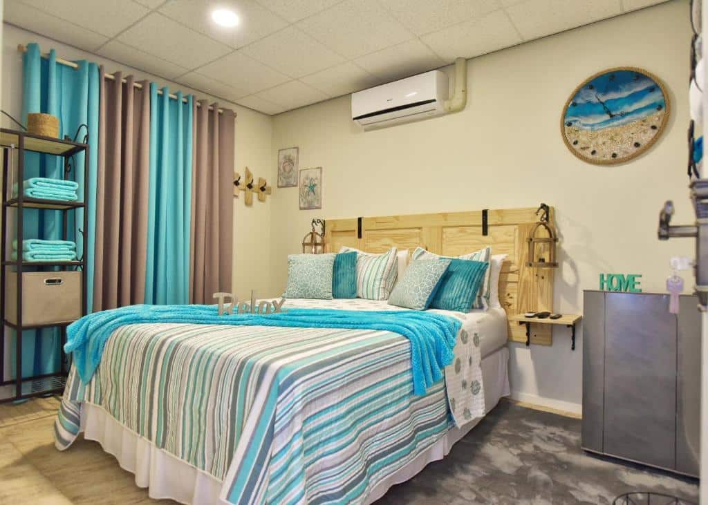 Uma cama bem arrumada do Turquoise B&B com roupa de cama listrada azul e bege em um quarto com detalhes em turquesa e decoração de parede.