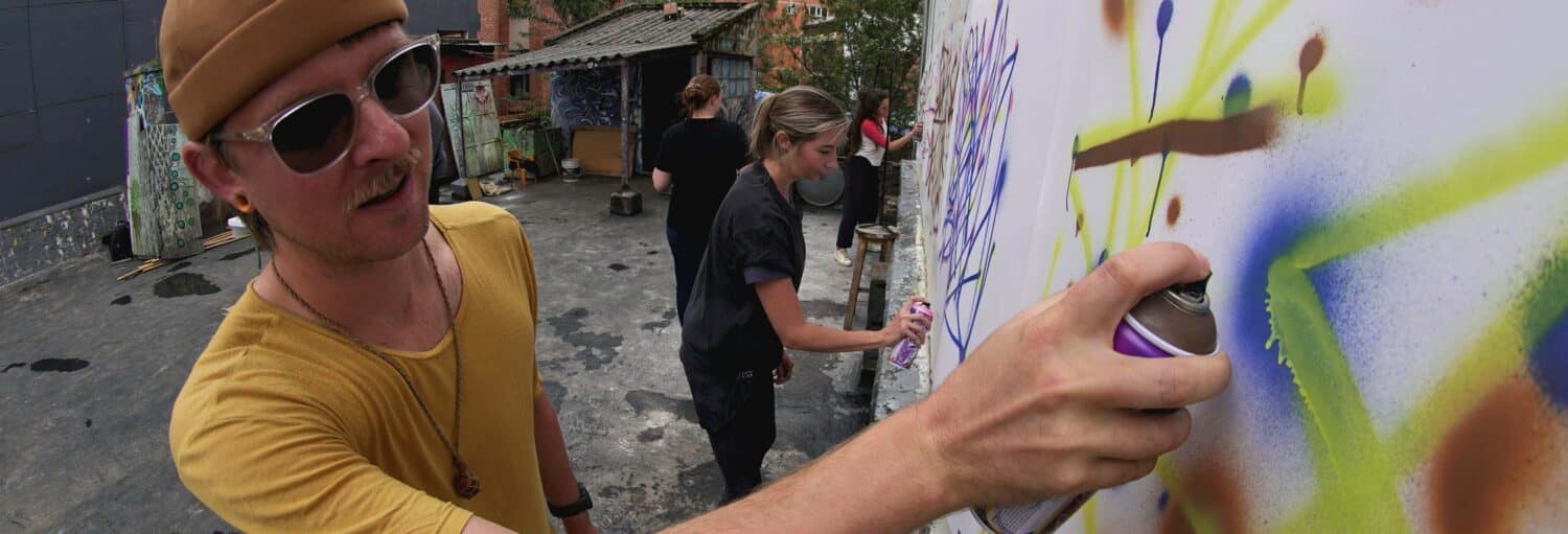Duas pessoas criam arte em grafite ao ar livre - uma Oficina privada de grafite em Bogotá com artistas pintando lado a lado.