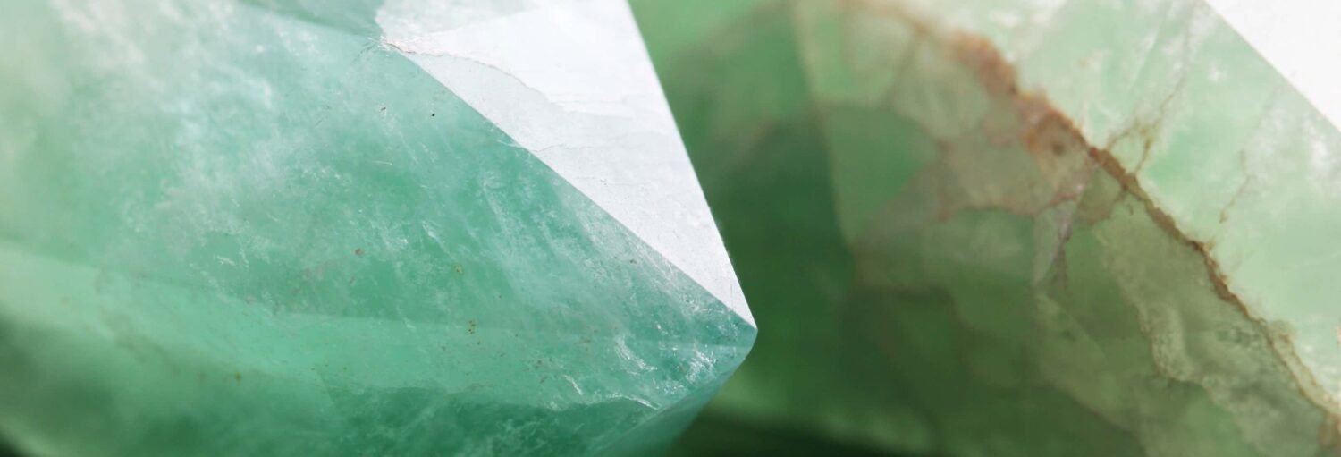 Vista de perto de dois cristais verdes com superfícies lisas e facetadas. A imagem ilustra o post sobre Tour privado da esmeralda por Bogotá.