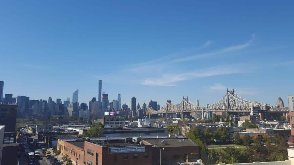 O horizonte de uma cidade com uma grande ponte suspensa e prédios altos sob um céu azul claro.