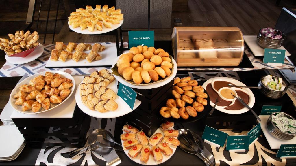 Uma mesa de bufê do Embassy Suites by Hilton com doces variados, pães, biscoitos, sanduíches e tigelas de chocolate e marmelada.