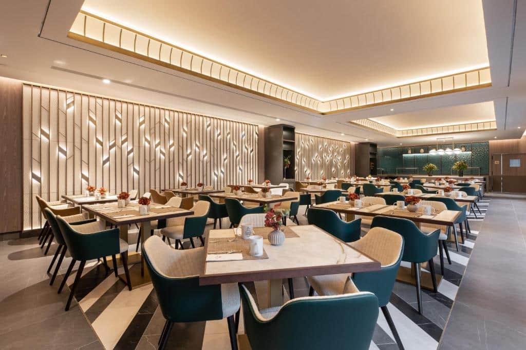 Área de jantar do restaurante do Eurostars Ambassador com mesas e cadeiras bem arrumadas, iluminação contemporânea e painéis de parede decorativos. Imagem para ilustrar post sobre onde ficar em Budapeste.