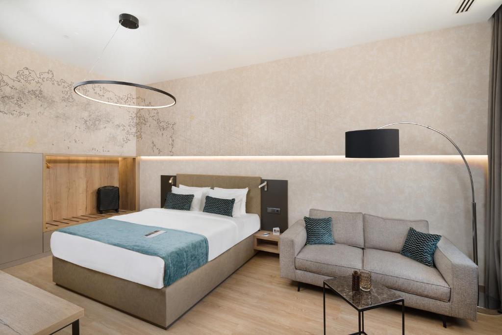 Quarto do Hotel Vision Budapest com uma cama de casal, detalhes em azul-petróleo, um sofá cinza, mesa lateral e decoração minimalista.