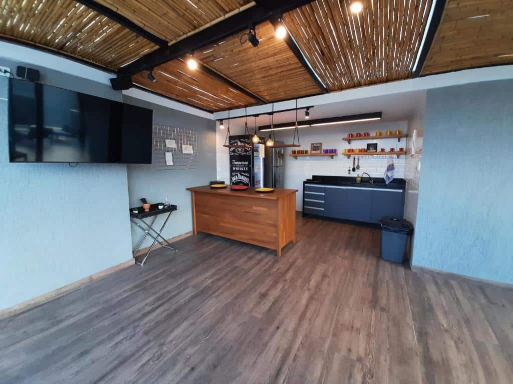 Uma cozinha moderna do Ház Jardim Guanabara com uma ilha de madeira, TV na parede, armários pretos e um teto de bambu.