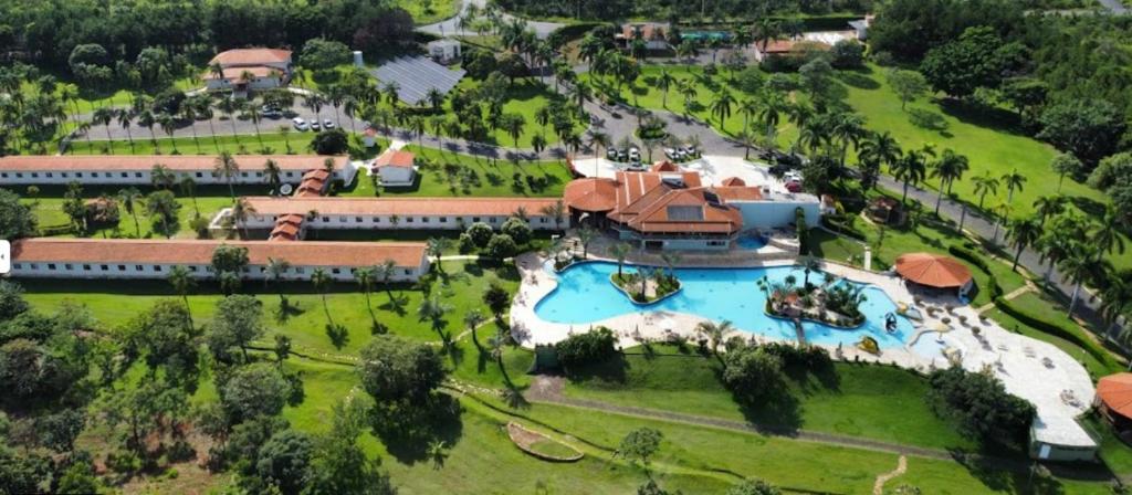 Vista aérea de um grande resort com piscina, edifícios com telhados vermelhos, palmeiras e gramados verdes, no Obbá Coema Village Hotel.