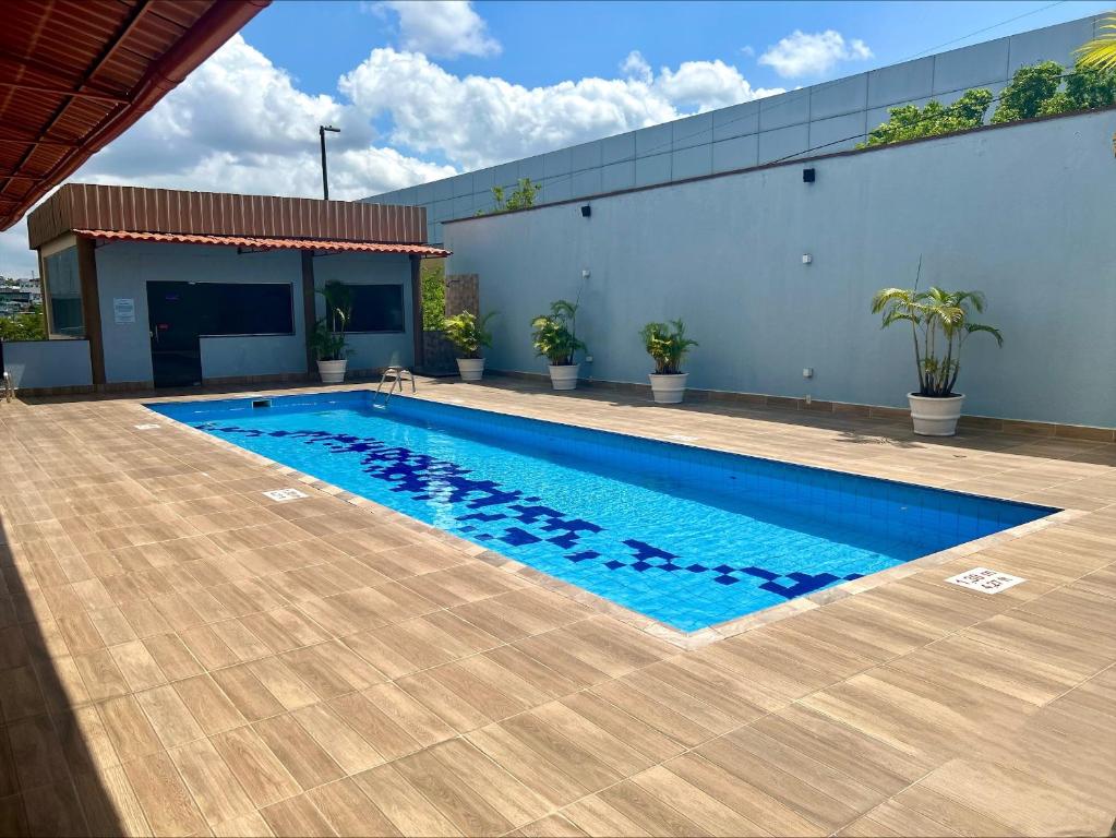 Piscina externa retangular com água limpa, deck de azulejos, vasos de plantas e um pequeno prédio ao fundo, no Sleep Inn Manaus. Representa hotéis em Manaus.