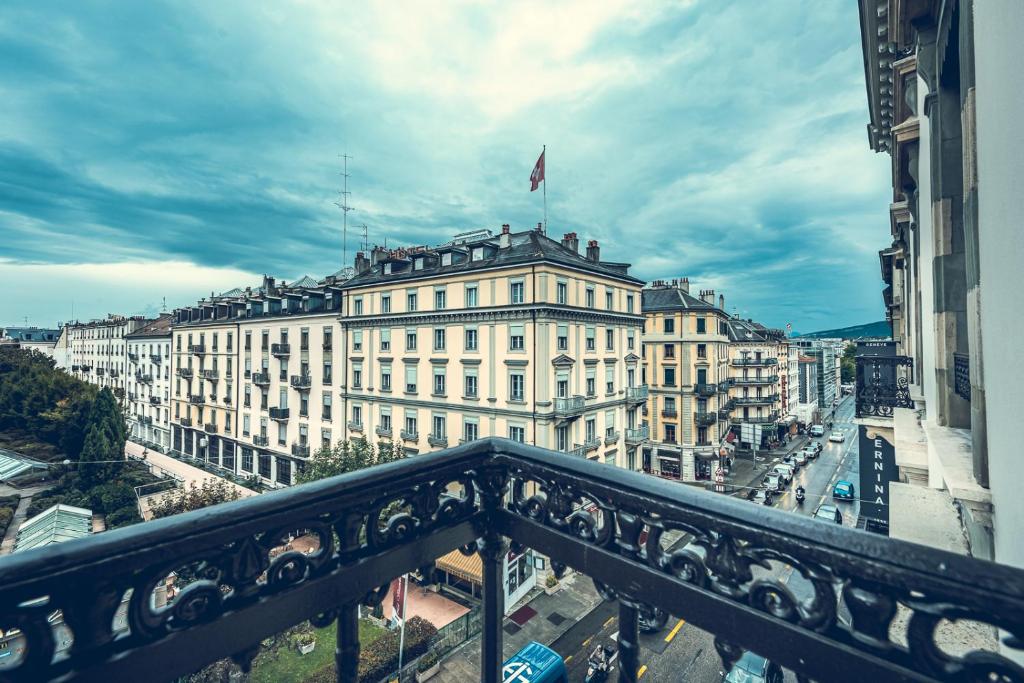 Vista de uma varanda do Hotel Bernina Geneva com vista para uma rua da cidade com edifícios históricos sob um céu nublado.