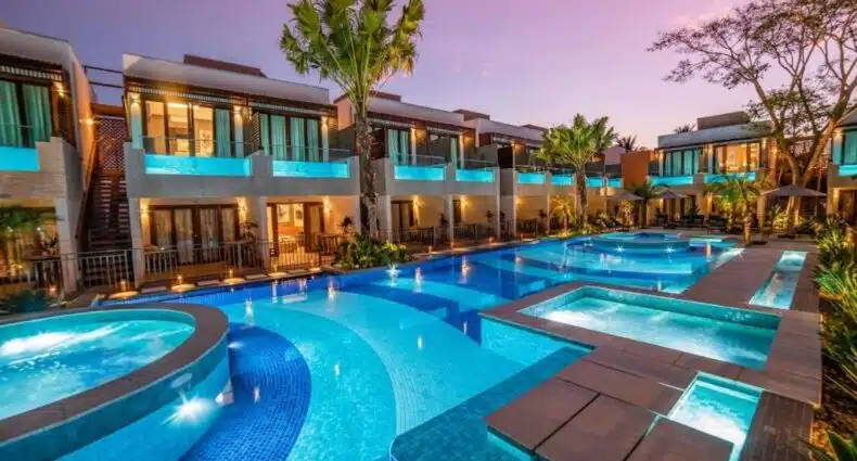 Arte da Natureza Hotel Bonito com quartos de dois andares com vista para uma grande piscina externa e banheiras de hidromassagem, iluminadas ao pôr do sol. Imagem para ilustrar post sobre onde ficar em Bonito.