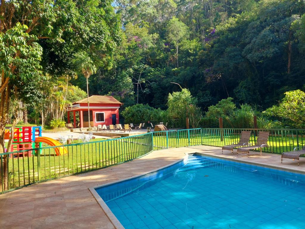 Hotel Vila Suíça 1818 com Área da piscina externa com espreguiçadeiras, uma seção cercada, um playground e um pequeno prédio vermelho cercado por árvores.