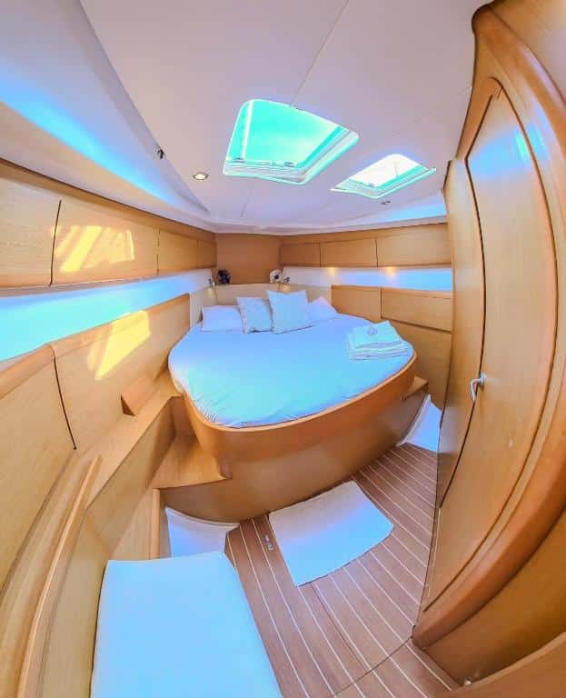 Uma cabine de iate na Private Sailingyacht "Guji" With Crew All Inclusive com uma cama de casal bem arrumada, paredes de madeira, armários embutidos e luz natural das janelas do teto. É uma das opções de onde ficar em San Blas.