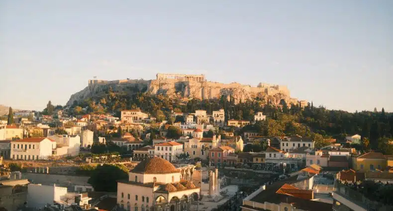 Vista panorâmica da cidade de Atenas, na Grécia, com a Acrópole e outros edifícios históricos ao fundo. A foto faz parte do post de onde ficar em Atenas.