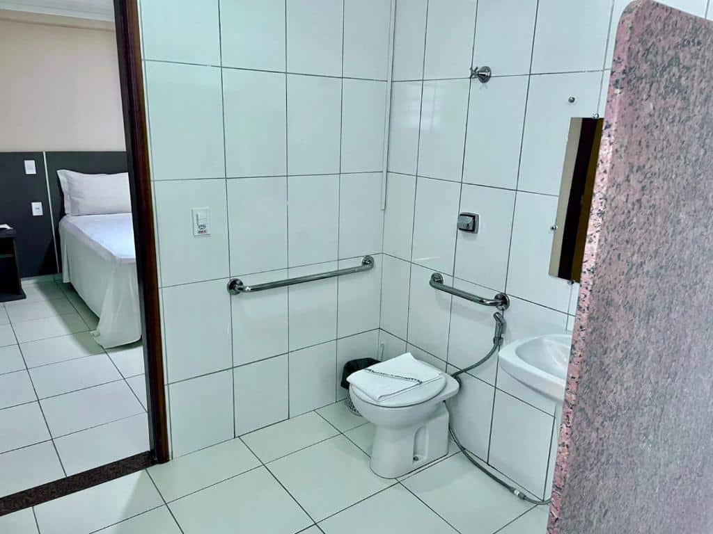 Banheiro da Pousada D' Areia equipado com vaso sanitário, barras de apoio e azulejos claros