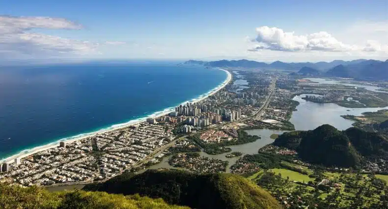 Vista panorâmica aérea da Bara da Tijuca, Rio de Janeiro, com sua impressionante orla, prédios, montanhas e mar azul-turquesa, para representar onde ficar na Barra da Tijuca.