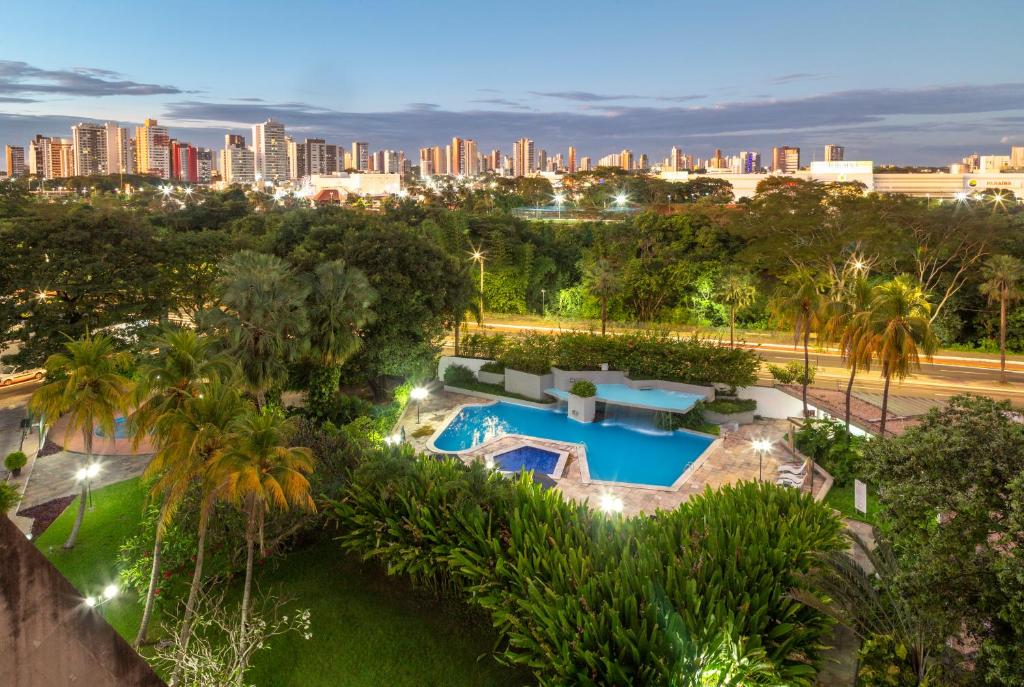 Skyline de Teresina visto do hotel Blue Tree Towers Rio Porty, com arranha-céus e edifícios iluminados ao entardecer, rodeada por vegetação tropical e piscina do hotel com luzes. A foto faz parte do post de onde ficar em Teresina.