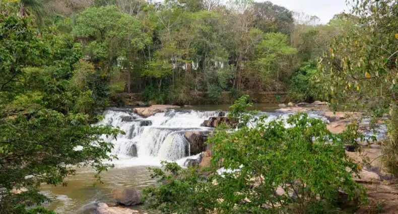 Cachoeira em meio à exuberante vegetação da Mata Atlântica brasileira, com água cristalina fluindo por entre as rochas e formando uma queda d'água, no Hotel Recanto da Cachoeira, para representar onde ficar em Socorro.
