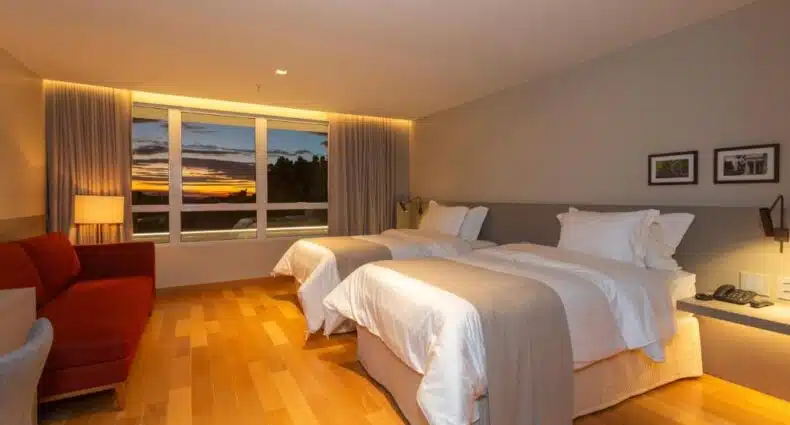 Quarto do Uchôa Teresina com vista para por do sol de Teresina sobre área arborizada. A foto é capa do post de onde ficar em Teresina.