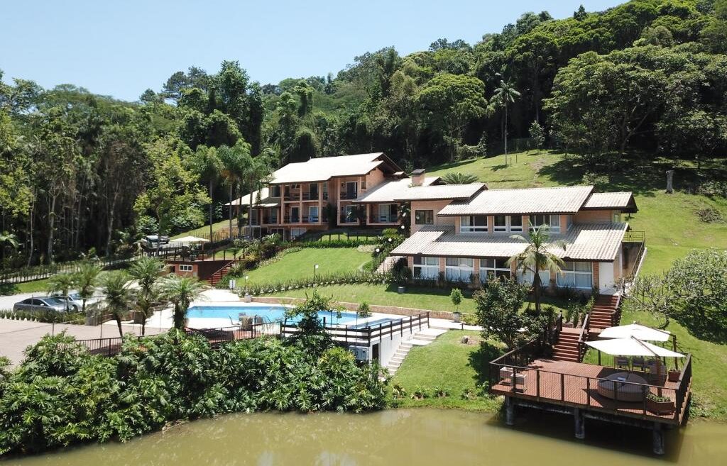 Complexo hoteleiro do Village Du Lac Hotel em meio a natureza com piscinas, decks de madeira e chalés aconchegantes.