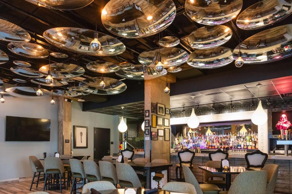 Elegante bar do Lorenzo Hotel Dallas com luminárias de vidro penduradas no teto e balcão com garrafas e copos decorativos, criando um ambiente sofisticado e acolhedor.