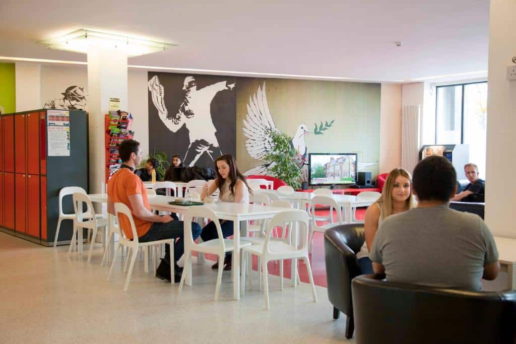 Pessoas reunidas em espaço de convivência no Abigail's Hostel com desenhos e decoração colorida nas paredes