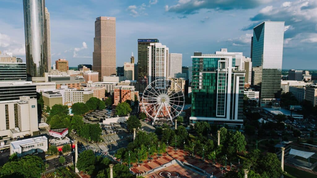 Vista panorâmica do Centennial Olympic Park, com roda-gigante e árvores, e dos edifícios de Atlanta atrás dele.