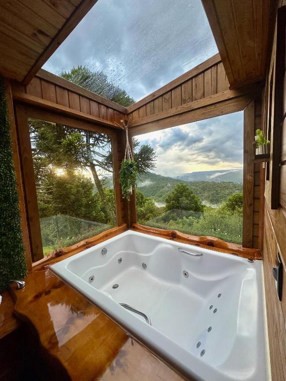 Banheira de hidromassagem de madeira com vista panorâmica para a natureza em cabana rústica no campo, na Pousada Flocos de Neve.