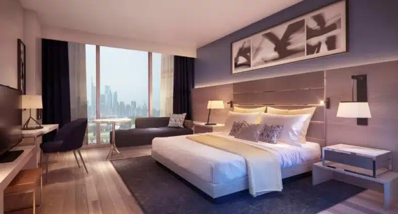 Quarto do Live! Casino & Hotel - Philadelphia com ampla janela com vista panorâmica para arranha-céus da cidade, decorado em tons neutros com quadro abstrato na parede. Representa onde ficar perto do Lincoln Financial Field.