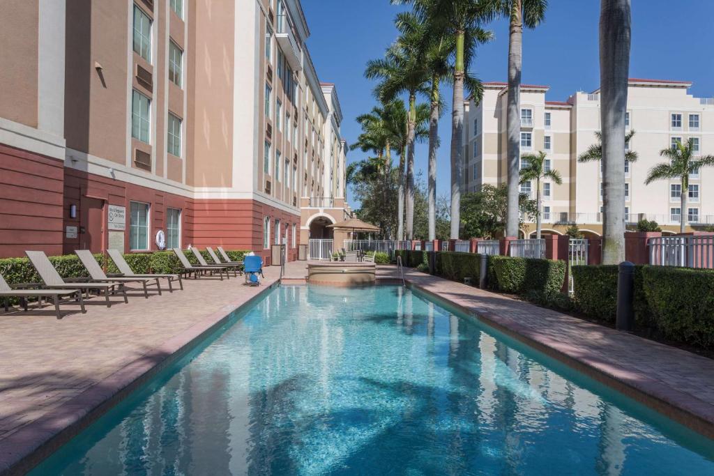 Piscina retangular com água azul no Hampton Inn & Suites Fort Lauderdale - Miramar com prédios e palmeiras ao redor