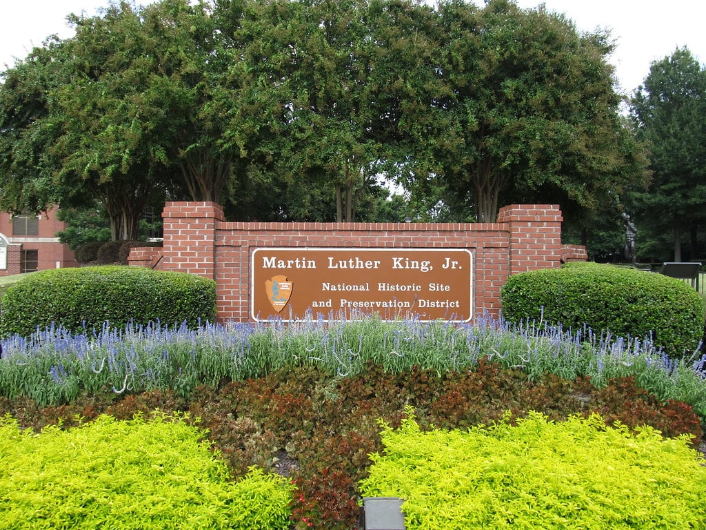 Placa de sinalização do Martin Luther King Jr. National Historical Park em meio a jardins e árvores.