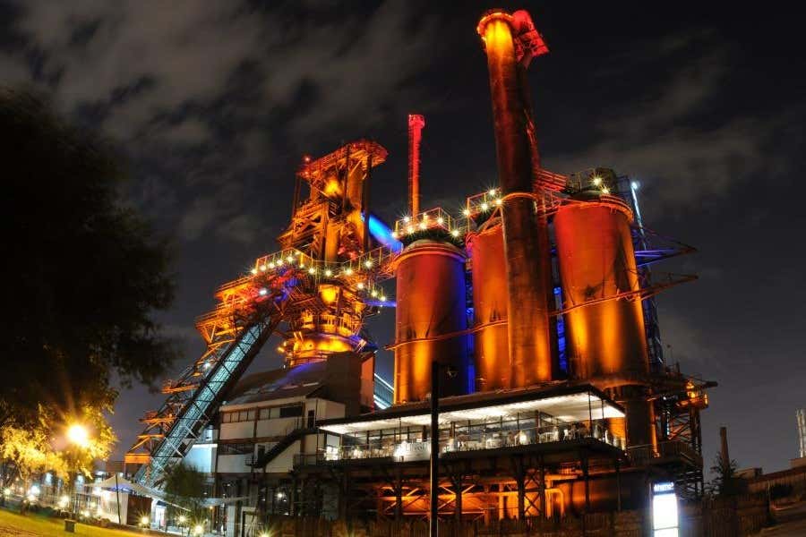 Usina de energia eólica com estruturas metálicas iluminadas durante a noite em ambiente industrial