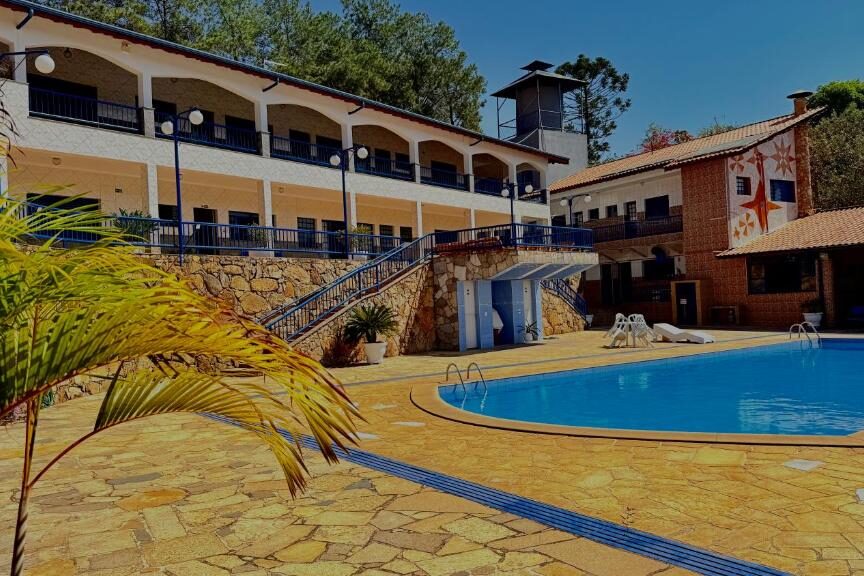 Resort Nova Aliança Suítes em estilo colonial cercado por vegetação, com piscina e sacadas em varandas ao redor.