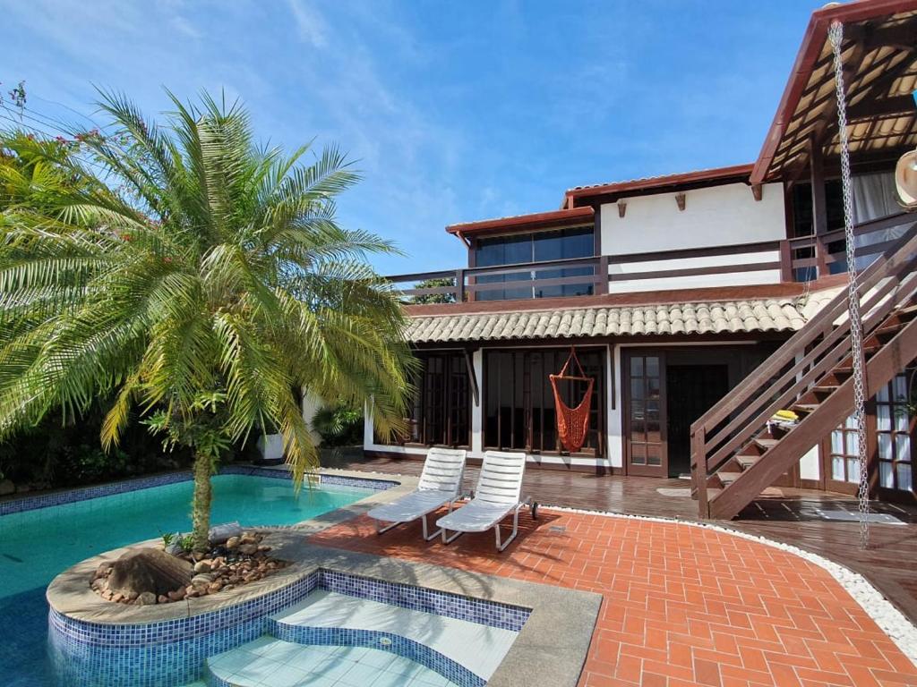 Casa de campo em estilo rústico com piscina, cercada por palmeiras e vegetação tropical em cenário ensolarado, do Guesthouse Mata da Praia.
