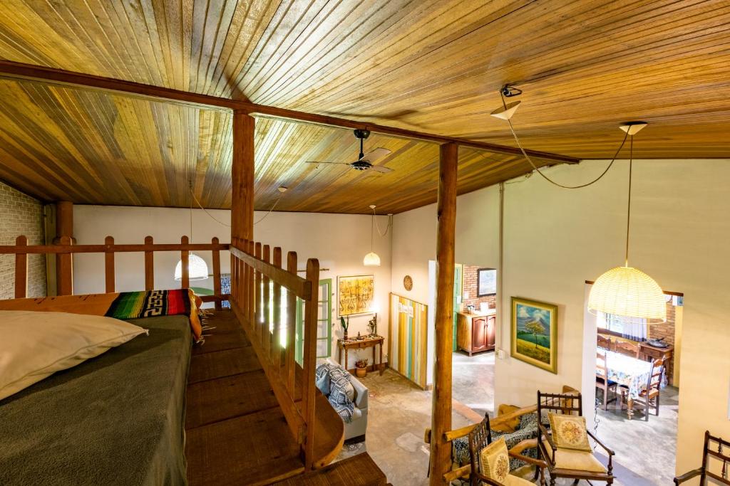 Loft rústico da Pousada Sítio Canto D`Água com teto abobadado de madeira, luminárias pendentes e móveis.