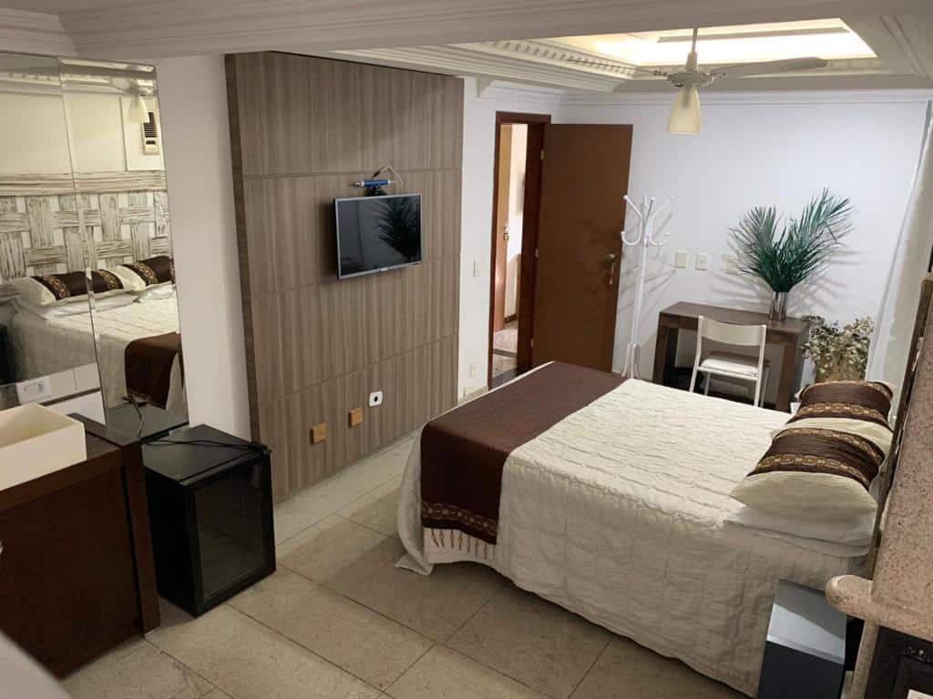 Quarto do Guesthouse Mata da Praia aconchegante com televisão embutida, móveis de madeira e decoração natural em tons neutros.