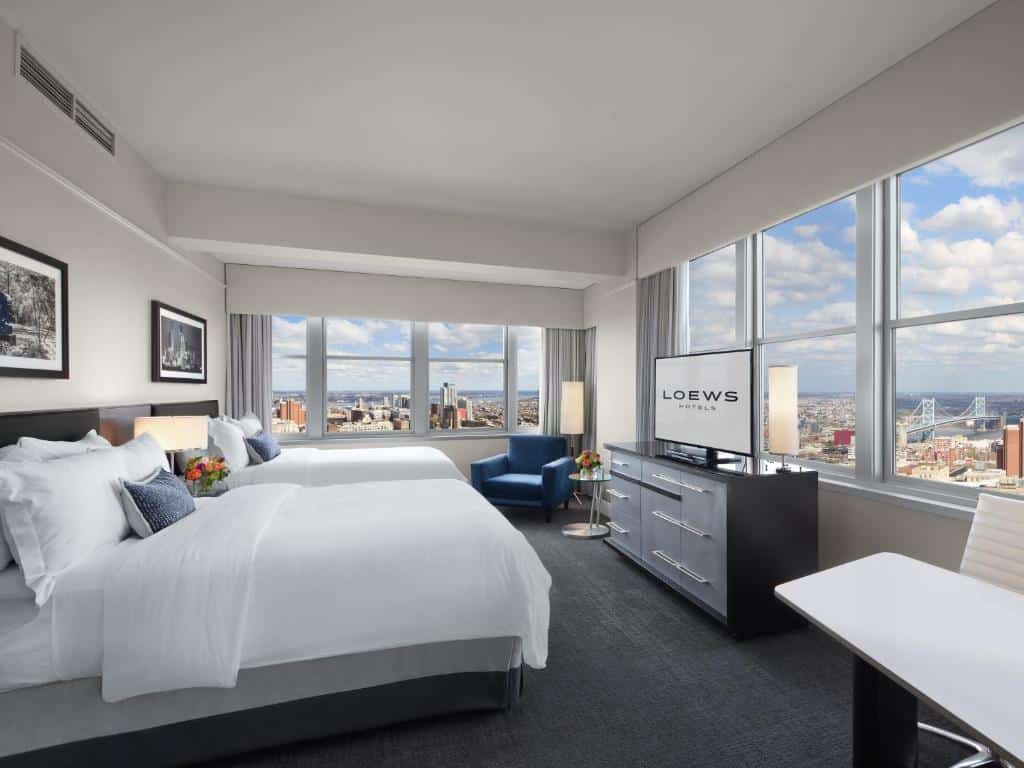 Quarto de luxo no Loews Philadelphia Hotel em prédio com vista panorâmica da cidade de São Paulo, com cama tamanho king, televisão de tela plana e móveis pretos elegantes, para representar onde ficar na Fialdélfia.