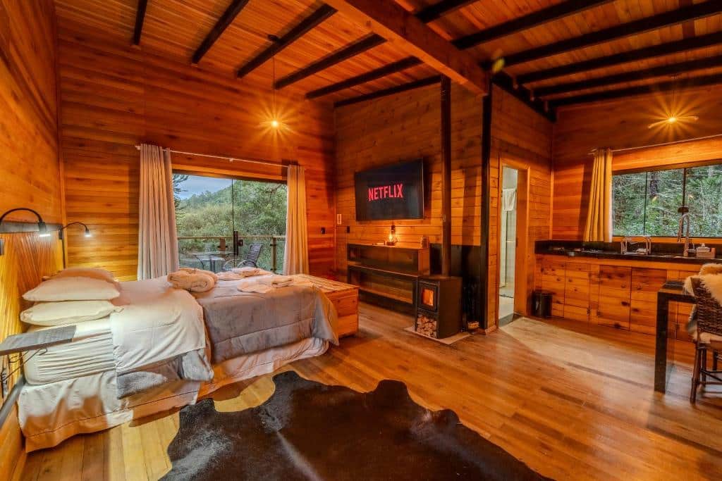 Aconchegante cabana de madeira com vista para a floresta, com cama confortável, TV com Netflix, lareira e pia rústica em ambiente agradável e acolhedor, na Pousada Cascata dos Amores, para representar onde ficar na Serra Catarinense.