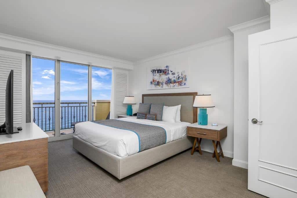 Quarto aconchegante do The Atlantic Hotel & Spa com vista panorâmica para o mar, decorado com móveis modernos e obras de arte na parede.