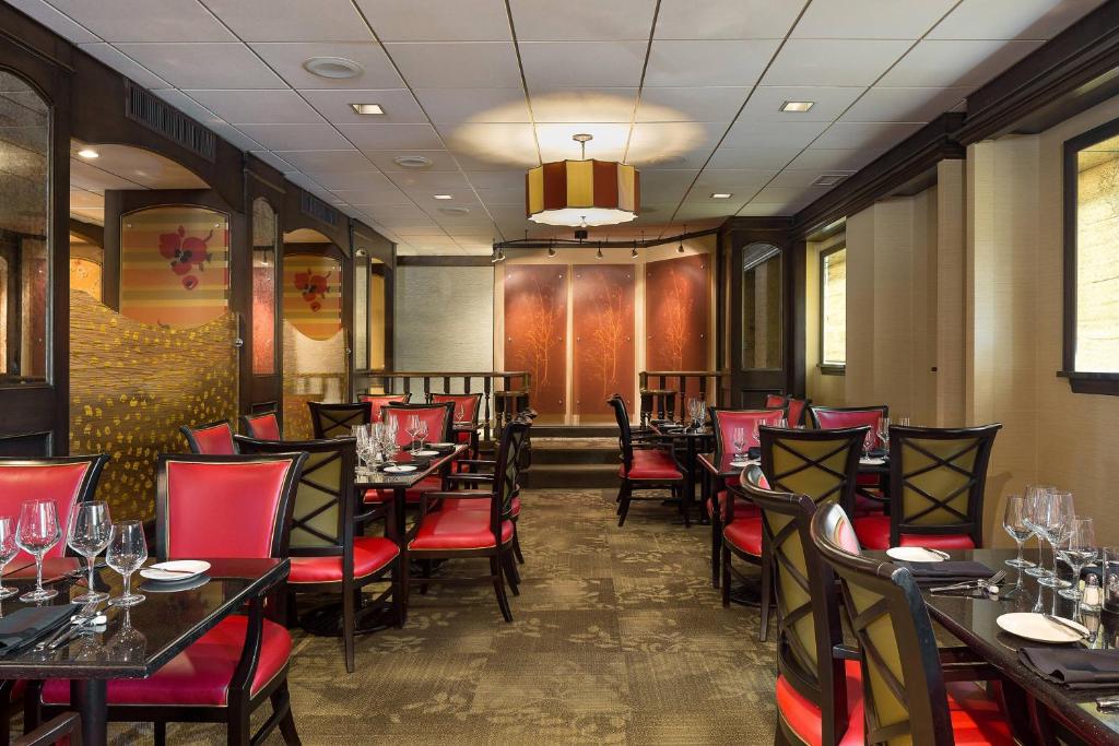 Restaurante elegante do The Raphael Hotel com decoração moderna em tons de marrom e vermelho, com mesas e cadeiras de estilo contemporâneo, lustres pendentes e obras de arte nas paredes.