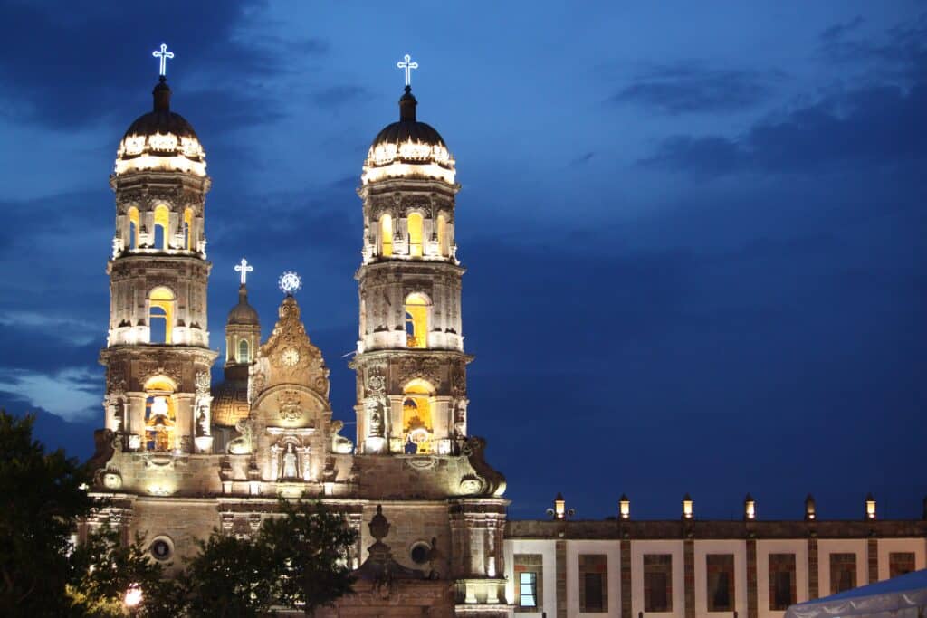 Basílica de Nossa Senhora de Zapopan com torres iluminadas em centro histórico da cidade à noite, para rperesentar onde ficar em Guadalajara.