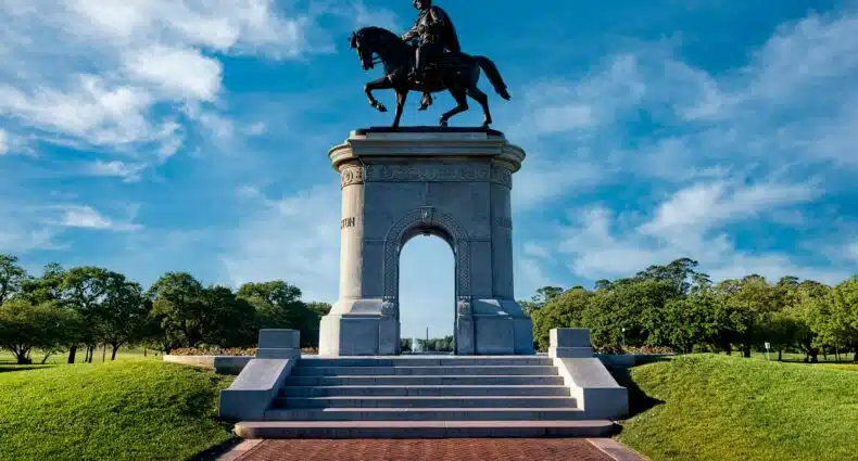 Monumento de estátua equestre de militar em praça pública com jardins e arco arquitetônico