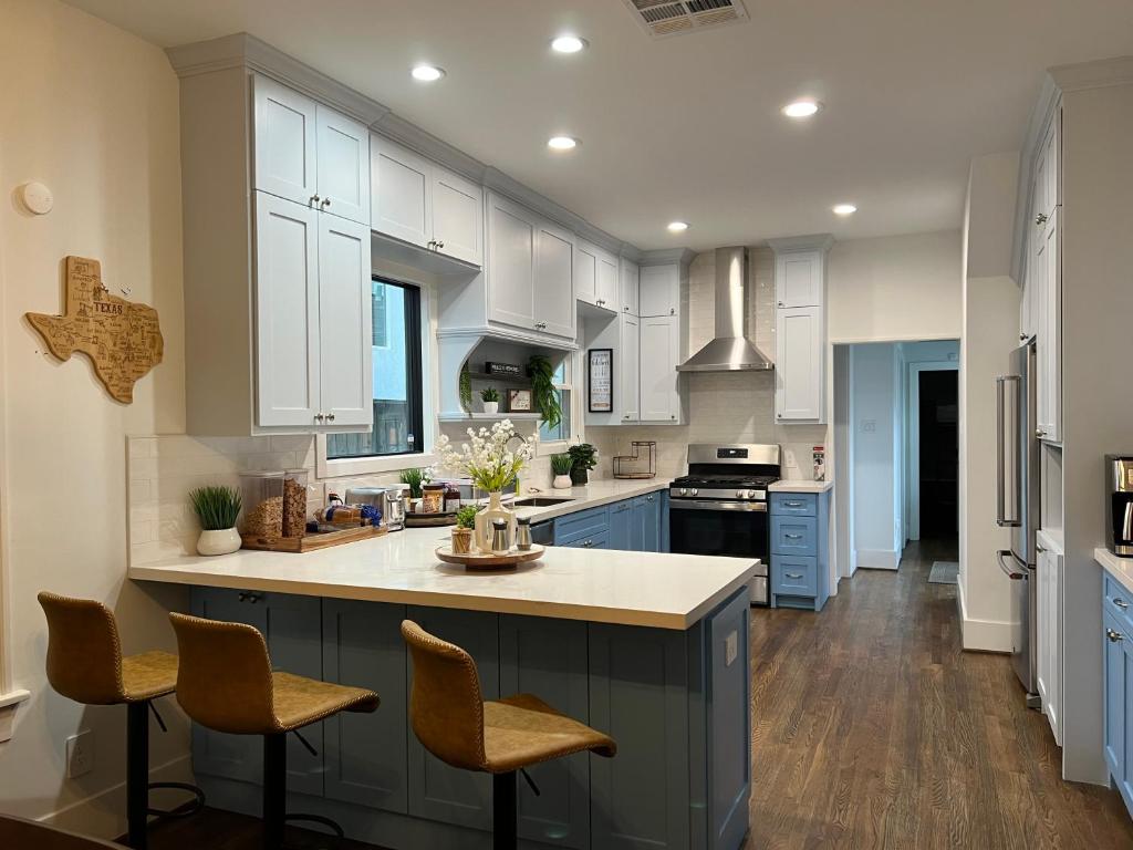 Cozinha espaçosa e moderna com armários brancos, ilha central com bancada de madeira, eletrodomésticos de aço inoxidável e decoração rústica com acessórios de madeira e plantas.