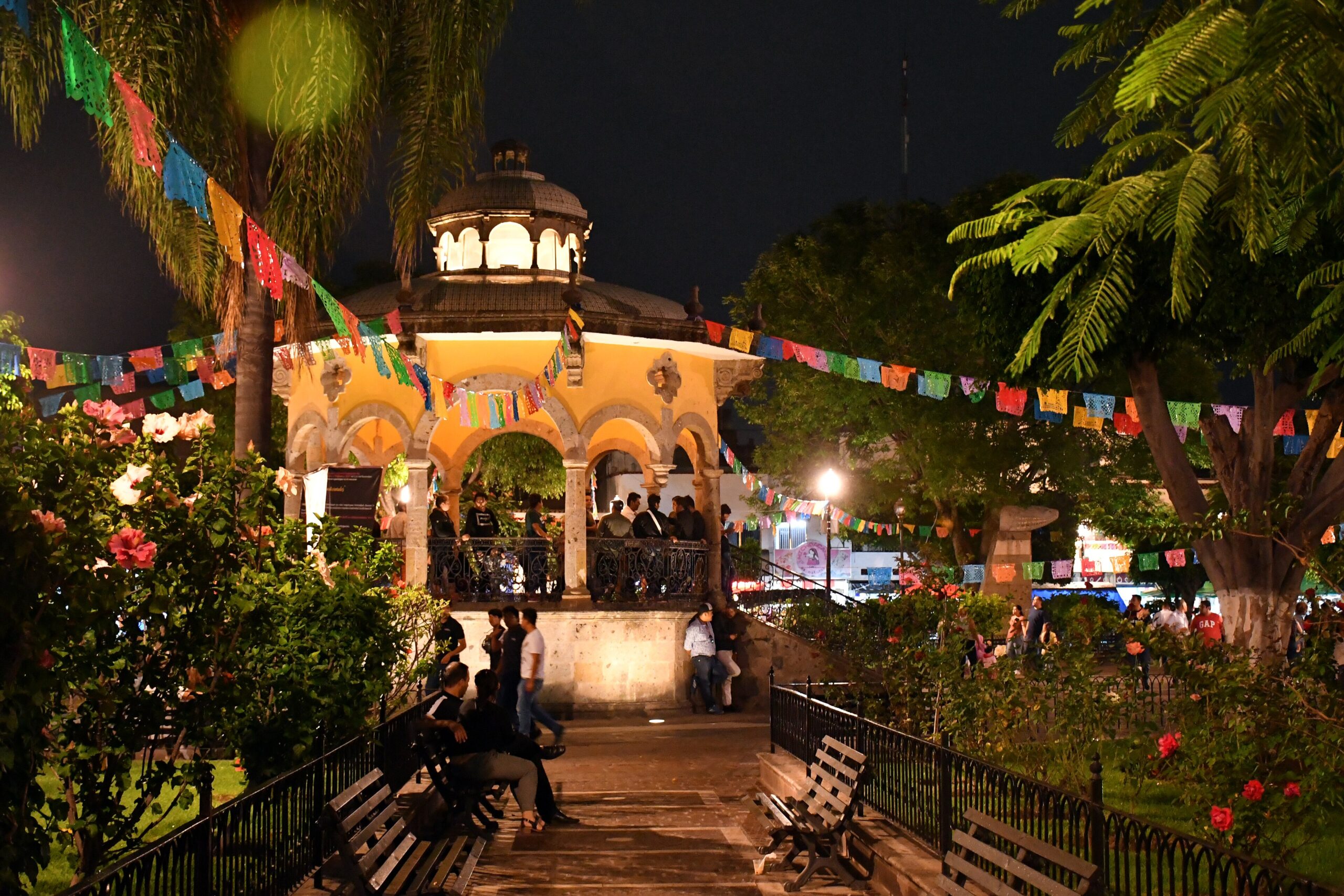 Jardim Hidalgo com quiosque iluminado e decoração típica de festa junina à noite em área ajardinada com palmeiras, em Tlaquepaque, para representar o que fazer em Guadalajara.
