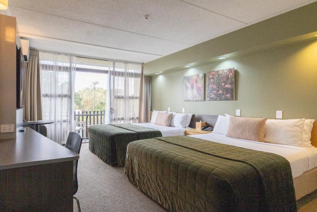 Quarto do Auckland Rose Park Hotel com duas camas de solteiro, mesa de trabalho e vista para área verde
