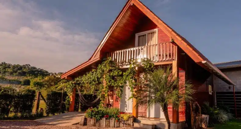 Chalé de madeira rústico com varanda e jardim florido, ideal para aluguel de temporada em área rural